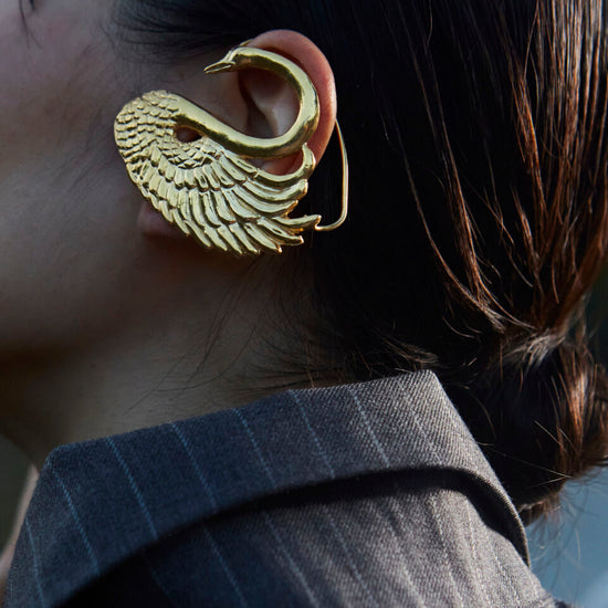 Zlatne minđuše Nola na azijskom modelu u sakou, od bronze u obliku labuda sa 24k pozlatom, organska skulpturalna forma - Neguj se