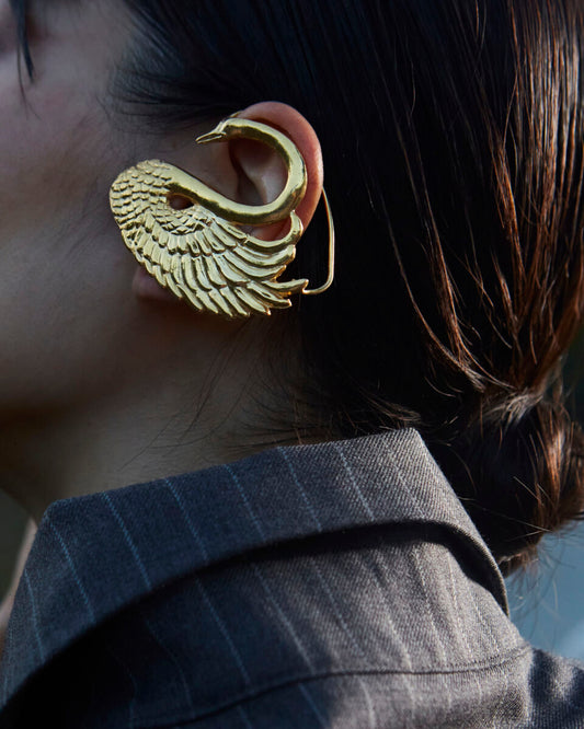 Zlatne minđuše Nola na azijskom modelu u sakou, od bronze u obliku labuda sa 24k pozlatom, organska skulpturalna forma - Neguj se